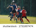 Small photo of Soccer players heading the ball in competition. Football adult game. Players in two teams compete for the ball. Footballers jumping high on the grass pitch