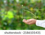 Small photo of Child's hands with downward CO2 emissions graph on natural green background