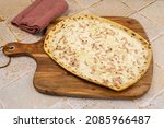 Small photo of flammekueche (flamed pie), Alsatian specialty, on a cutting board