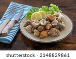 Small photo of cooked whelks on a plate with salad and lemon