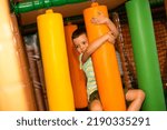 A cute cheerful child on a colorful obstacle course in a children's play center.
