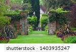 Small photo of TICEHURST, EAST SUSSEX, ENGLAND - MAY 18, 2019: Garden Gate with Plants and Statue.