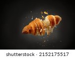 Falling delicious fresh baked croissant on black background. French pastry
