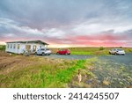 Isolated home with parked cars at sunset, Iceland.