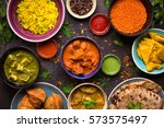 Assorted indian food on dark wooden background. Dishes and appetizers of indian cuisine. Curry, butter chicken, rice, lentils, paneer, samosa, naan, chutney, spices. Bowls and plates with indian food