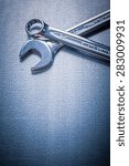 Small photo of Stainless flat spanner and hook wrench on metallic background construction concept