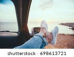 Fall car trip in sunset. Freedom travel concept. Spending weekend in roadtrip. Woman feet on car window, watching the sea.