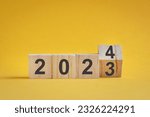 Wooden cube stock flipping, change from 2022 to 2023. Yellow color background, with copy space.