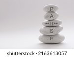 Yoga zen stones balancing on top of each other with pause symbol