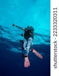 Small photo of Silhouette of scuba diver completing safety stance with SMB device deployed. Bubble underwater. Bubbling divers. Scuba Diver Facing Surface at Safety Stop. Daedalus reef, Egypt.