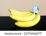 Small photo of isolated fresh organic ripe yellow banana fruit protection or preservation from turning brown and keep fresh longer with aluminium foil cap wrap