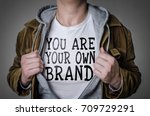 Man showing You Are Your Own Brand tittle on t-shirt. Personal branding concept.
