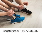 Couple tying up laces on sport shoes closeup. Unrecognizable man and woman preparing for training, wearing sneakers, copy space