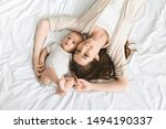 Happiness of motherhood. Smiling mother and her cute little infant baby lying on bed, top view