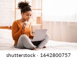 African American Lady Using Laptop Having Coffee Sitting On Bed At Home Relaxing On Weekend Morning. Empty Space, Selective Focus
