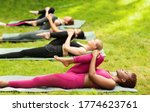 Group of diverse girls stretching their leg during yoga class outside, copy space. Panorama