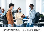 Small photo of Healthcare, Education, Lifestyle And People Concept. Group of smiling diverse international students wearing protective medical masks and talking, standing in lecture hall at the university