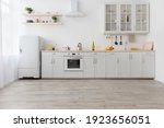 Small photo of Rent of modern housing sale of new apartment, modern renovation. White furniture with utensils, shelves with crockery and plants in pots, refrigerator in simple minimal dining room, empty space