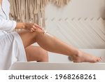 Unrecognizable Woman Shaving Legs Using Safety Razor Removing Hair In Modern Bathroom At Home. Female Making Depilation Sitting On Bathtub Indoors. Hygiene And Beauty Routine. Side View, Cropped