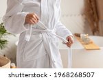 Wellness And Spa. Unrecognizable Woman Untying White Bathrobe Preparing For Beauty Ritual In Modern Bathroom In Hotel Or Spa Center. Female Body Care And Pampering. Cropped Shot