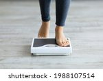 Unrecognizable young Indian woman stepping on scales to measure her weight at home, closeup of feet. Cropped view of millennial lady checking result of her slimming diet. Healthy living concept