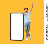 Small photo of Yes, Big Luck. Excited Guy Leaning On Smart Phone With Empty White Screen Shaking Clenched Fist Raising Hand Up, Cheerful Man Celebrating Win, Looking At Camera, Standing At Studio, Mock Up Collage
