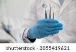 Small photo of Unrecognizable Dentist Doctor In Blue Sterile Glove Holding Dental Tools In Hand, Demonstrating Mouth Mirror, Probe And Stainless Tweezers, Creative Banner For Quality Stomatological Services