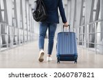 Unrecognizable Man With Bag And Suitcase Walking In Airport Terminal, Rear View Of Young Male On His Way To Flight Boarding Gate, Ready For Business Travel Or Vacation Journey, Cropped, Copy Space
