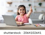 Small photo of Distant Learning. Little Arab Girl Showing Thumb Up While Study With Laptop At Home, Smiling Female Child Sitting At Table With Computer In Living Room, Recommending Online Education, Copy Space