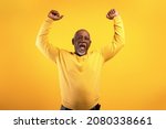 Small photo of Overjoyed senior black man screaming in excitement, gesturing YES with both hands on orange studio background. Triumphant elderly African American male shouting WOW, celebrating his success