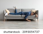 Small photo of Lack of Energy Concept. Full Body Length Of Exhausted Sleepless Young Man Lying On The Couch With Face Down, Tired In The End Of Hard Working Day, Fatigued Middle Eastern Male Resting At Home