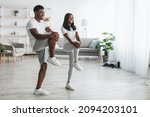 Cardio Workout. Black Couple Training Together In Living Room, Doing High Knees Exercise. Couple Warming Up Standing Lifting Leg Up To Chest, Stratching Hamstring Muscles, Looking At Free Copy Space