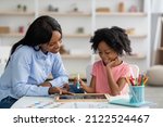 Small photo of Friendly young african american woman speech therapist teaching adorable little kid alphabet, drawing letters on blackboard with chalk. Speech-language therapy for children concept