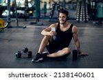 Small photo of Fitness Application. Smiling Middle Eastern Sportsman Using Smartphone At Gym While Relaxing After Training, Handsome Arab Male Athlete Browsing New Mobile App With Workout Tutorials, Copy Space