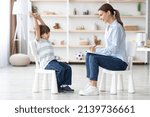Small photo of Cute talkative little boy telling funny story to professional woman psychologist during personal consultation, therapist taking notes about patient's mental health