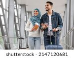 Small photo of Portrait Of Joyful Islamic Spouses Standing With Luggage, Passports And Smartphone At Airport, Happy Muslim Couple, Arab Man And Woman In Hijab Travelling Abroad Together, Ready For Trip, Copy Space