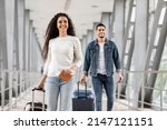 Air Travels Concept. Portrait Of Happy Man And Woman Walking With Suitcases In Airport, Smiling Arab Male And Female Going With Luggages To Departure Gate, Enjoying Travelling, Copy Space