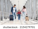 Small photo of Traveling Together. Joyful Arabic Family Walking With Suitcases At Airport Terminal, Happy Middle Eastern Parents And Female Kid Carrying Luggage While Going To Flight Departure Gate, Copy Space