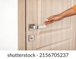 Cropped Shot Of African American Woman Opening Door Of Her Home, Closeup Of Female Hand Reaching For Handle Standing In Doorway Indoors. Real Estate Ownership Concept