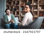 Small photo of Happy millennial black woman psychologist in glasses look at camera, consulting smiling european man in office clinic interior. Therapy, mental problems, psychologist support and professional help