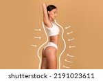 Small photo of Liposuction concept. Drawn outlines with arrows around fit lady in white underwear, slender woman with perfect figure posing over beige studio background, collage