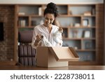 Small photo of Excited pretty young woman customer opening paper box parcel, holding stylish brand new white sneakers and smiling, female buyer shopaholic checking her delivery from webstore at home, copy space