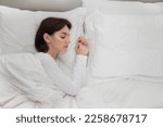 Small photo of Top view of young brunette woman in white pajamas sleeping alone in big bed at home, female going through breakout, divorce, lifetime crisis, copy space for advertisement next to lady