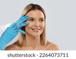 Happy pretty blonde middle aged woman gets cosmetic eye injection, copy space, closeup. Hyaluronic acid injection for facial rejuvenation procedure. Women in beauty salon. Plastic surgery clinic.