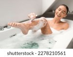 Body Hair Removal. Happy Woman Shaving Legs Using Safety Razor Caring For Herself Bathing In Modern Bathroom At Home. Depilation And Skincare Cosmetics Concept. Selective Focus
