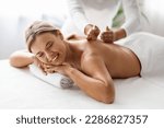 Small photo of Beautiful Middle Aged Woman Enjoying Professional Wellness Massage In Spa Salon, Closeup Shot Of Therapist Lady Massaging Back Of Attractive Mature Female Lying On Table With Closed Eyes