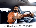 Car Owner. Joyful Middle Eastern Man Smiling Posing Holding Automobile Wheel, As He Driving Testing New Vehicle. Shot Of Happy Bearded Driver Guy Sitting In Own Comfortable Auto