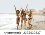 Happy female friends piggybacking each other on the beach, women smiling cheerfully while having fun on coastline. Best friends enjoying their vacation together