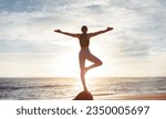 Small photo of Glad young caucasian woman enjoy workout, freedom, peace and meditation, breathing exercises, practicing yoga on sea beach, back, sun flare. Health care, balance, vitality outdoor