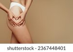Small photo of Young caucasian lady in underwear making heart sign with hands on hip, isolated on beige studio background, cropped. Weight loss, self love, body positive, wellness and skin care, moistening